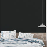 Black matte wallpaper in modern living room creating dramatic backdrop for colorful furniture