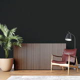 Home office with black matte accent wall showcasing art pieces