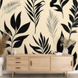 Black and beige tropical leaves wallpaper creating a modern accent wall in a bright minimalist living room setting