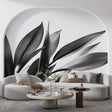 Black and white botanical leaf mural wallpaper styled in a modern living room with minimal furniture and natural light