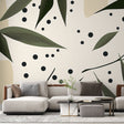 Modern botanical wallpaper with leaves and dots pattern shown in a bright living room with minimal furniture