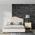 Black brick wallpaper in modern living room with grey sofa and industrial lighting