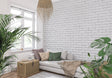 White brick mural wallpaper in modern living room with gray sofa and plants