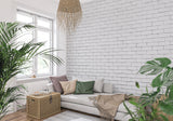 White brick mural wallpaper in modern living room with gray sofa and plants