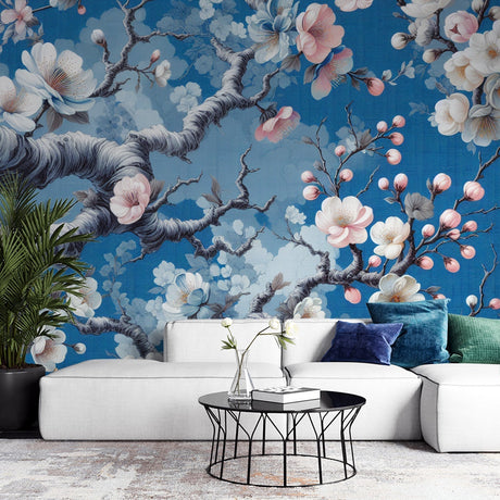 Cherry blossom wallpaper mural showcased in a modern living room, pink petals against blue sky creating depth
