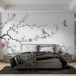 Cherry blossom wallpaper with birds in a bright modern bedroom, pink petals float across white walls creating a peaceful atmosphere
