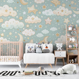 Cloud and star wallpaper in a cozy nursery with white crib, showing the perfect blend of mint green and golden stars