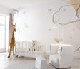 Cloud and bee nursery wallpaper in a bright modern nursery with white furniture and natural light