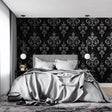 Black and silver damask wallpaper in modern living room with grey sofa and crystal chandelier