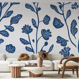 Blue and orange botanical wallpaper mural shown in a bright modern living room, creating a fresh and lively atmosphere