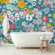 Floral wall mural with yellow and pink blooms on teal background brightening a modern living room with natural light