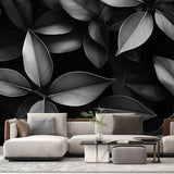 Black and white leaf pattern mural wallpaper creating drama in a modern living room with minimal furniture
