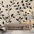 Black botanical leaf wallpaper mural in modern living room with gray sofa and natural light
