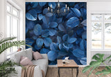 Blue leaf wallpaper mural creating depth in a modern living room with grey sofa and natural light