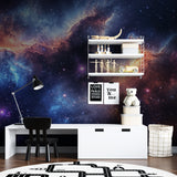 Galaxy wallpaper mural shown in modern bedroom with blue nebula patterns creating a dreamy atmosphere