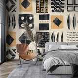 Geometric tribal wallpaper with black and gold patterns creating drama in a modern living room with minimal furniture