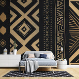 Black and gold geometric tribal wallpaper in modern living room creating dramatic accent wall with warm lighting