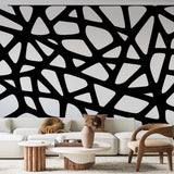 Modern geometric wallpaper creating dramatic impact in a minimalist living room with black and white furniture
