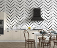 Modern black and white geometric wallpaper creating depth in a minimalist living room setting