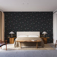Modern geometric wallpaper showcased in a minimalist living room with black furniture and large windows