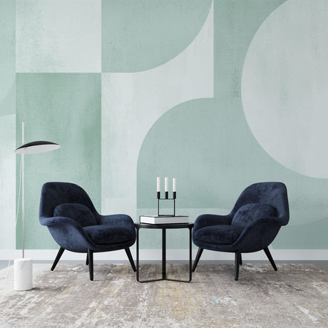 Modern geometric wallpaper in sage green tones shown in a bright living room setting with minimal furniture