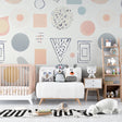 Geometric nursery wallpaper with pastel shapes brightening a modern baby room with white furniture