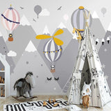 Hot air balloon nursery wallpaper creating a dreamy atmosphere in a soft pink kids bedroom with mountain views