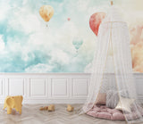 Hot air balloon wallpaper creating a dreamy atmosphere in a bright nursery with white furniture