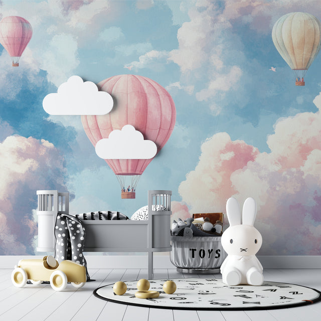 Hot air balloon wallpaper in a bright nursery with white furniture showing soft pink and blue tones