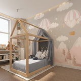 Nursery accent wall with pink balloon and cloud pattern beside rocking chair