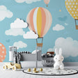 Hot air balloon wallpaper in a bright nursery with white furniture, showing floating pastel balloons against a gentle blue sky