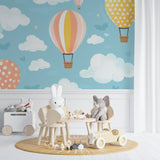 Kids bedroom featuring hot air balloon mural wallpaper with soft pastel colors and playful cloud patterns