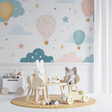 Hot air balloon wallpaper in a cozy nursery with rocking chair and white crib, soft pastel colors create a dreamy atmosphere