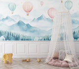 Hot air balloon wallpaper in a bright nursery, pink and mint balloons floating above misty mountains