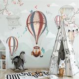 Whimsical hot air balloon wallpaper brightening a neutral nursery with wooden accents