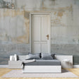 Industrial door mural wallpaper creating depth in modern living room with gray sofa and plants