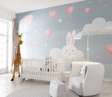 Bunny nursery wallpaper in a modern white nursery with gray rocking chair and pink accessories