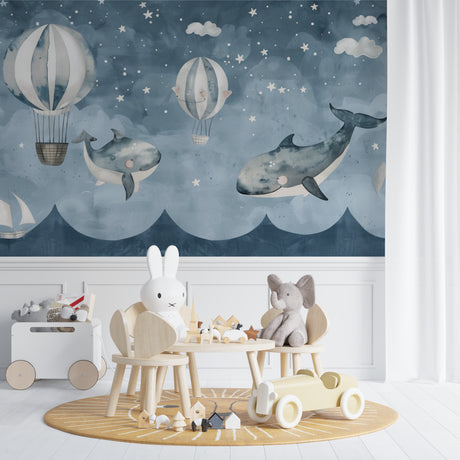 Whale and balloon wallpaper mural in a modern nursery with white furniture and soft lighting