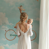 Toddler room featuring whimsical giraffe cycling wallpaper behind white furniture