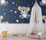 Nursery wall mural with koala and stars in a playroom setting with white furniture