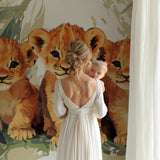 Lion Cubs Wallpaper in bright modern nursery, showing three playful cubs among tropical leaves