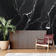 Black marble wallpaper creating dramatic impact in modern living room with white furniture