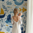 Marine animals wallpaper displayed in a bright nursery with white furniture, showing playful whales and boats