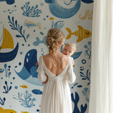 Marine animals wallpaper displayed in a bright nursery with white furniture, showing playful whales and boats