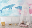 Marine animals wallpaper displayed in a bright nursery, showing watercolor whales floating across pastel walls