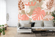 Modern living room with Monstera leaf wallpaper in coral and beige tones, creating a fresh botanical atmosphere