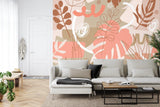 Modern living room with Monstera leaf wallpaper in coral and beige tones, creating a fresh botanical atmosphere