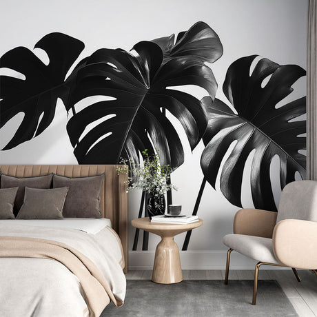 Black and white Monstera leaf wallpaper creating a dramatic statement wall in a modern living room with minimal furniture