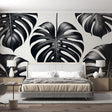 Modern black and white Monstera leaf wallpaper creating a striking focal point in a minimalist living room setting