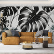 Modern living room with black and white Monstera leaf wallpaper creating dramatic impact against neutral furniture